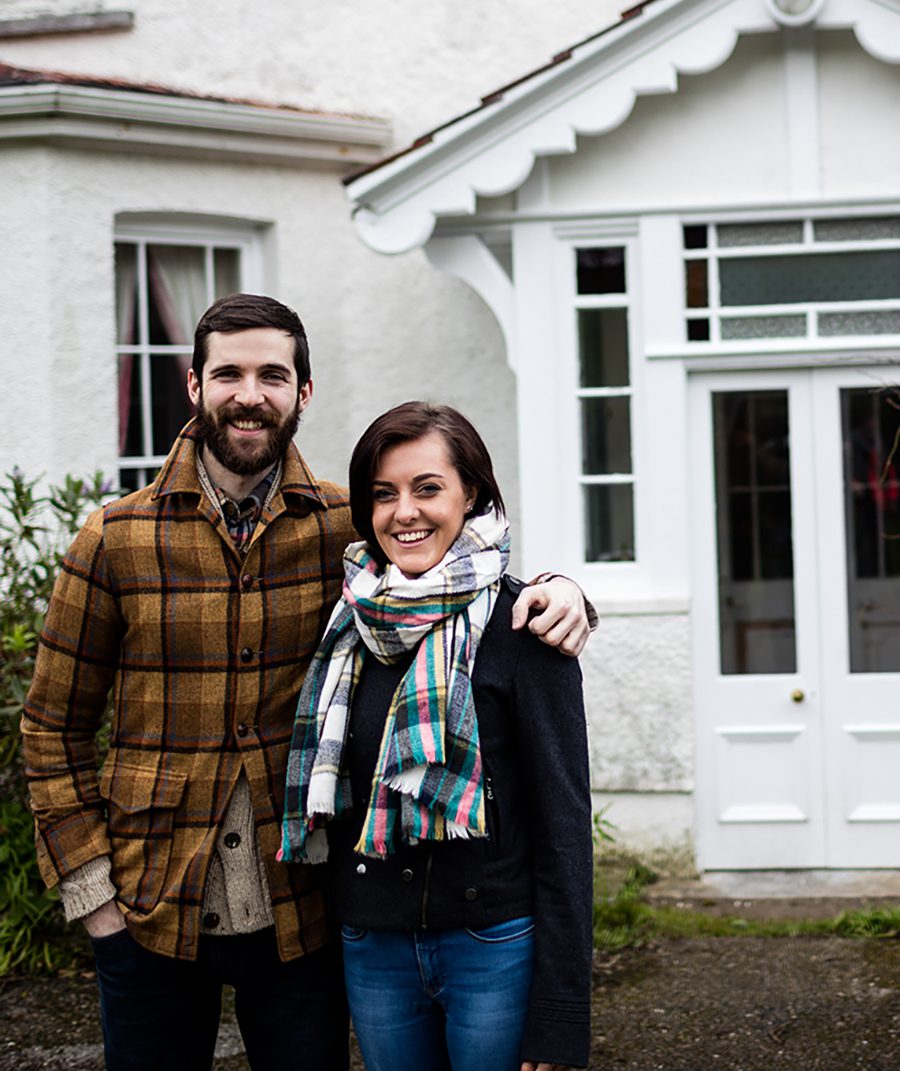 Portrait of couple standing near a new house with arms around